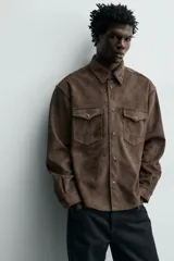 Sobrecamisa de corte regular fit confeccionada en tejido con efecto ante. Presenta cuello solapa, cierre frontal con botones a presión, mangas largas con puños abotonados y dos bolsillos de plastrón con solapa en el pecho.