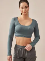 Top deportivo corto color verde azulado, de mangas largas y escote redondo.