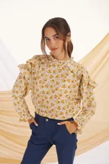 Blusa de manga larga con estampado floral en tonos mostaza y lila, con cuello y puños con volados.