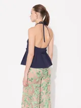 Top azul marino de poplín elastizado, con cuello halter que se ata con lazo. Tiene espalda descubierta y faldón con tablas superpuestas.