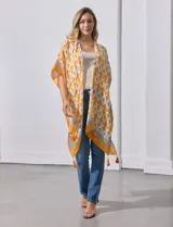 Kimono tejido con estampado abstracto en tonos azules, blancos y violetas. Tiene terminación de ruedo con borlas.
