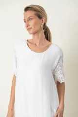 Vestido blanco de seda con mangas cortas y bajo con detalles de broderie.