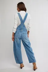 Jardinero enterito de denim en color azul claro, con diseño de peto, tiras regulables y botones laterales. Presenta corte amplio estilo barrel con piernas abuchonadas y bolsillos frontales.