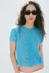 Chaqueta de punto confeccionada con mezcla de lana y alpaca, color celeste, de manga corta, cuello redondo y cierre frontal con botones.