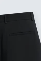 Pantalón de corte relajado en color verde militar, con diseño de pliegues frontales, bolsillos laterales y cierre de cremallera con botón.