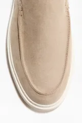 Mocasines de gamuza color beige con acabado cepillado, costuras tradicionales en el empeine y suela de goma blanca.