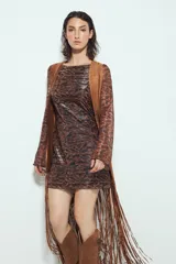 Chaleco largo de gamuza color marrón, con diseño abierto, flecos largos en el ruedo y apliques metálicos decorativos en el frente.