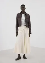 Falda larga color beige de algodón, con diseño evasé, tiro medio, forro interior y detalle cruzado tipo pañuelo con cierre de nudo en la cintura.