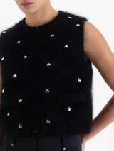 Top sin mangas de cuello redondo y corte cropped, confeccionado en tejido de angora y lana con textura suave. Presenta apliques metálicos en forma de corazón distribuidos por toda la prenda.