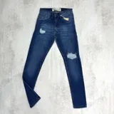 Jean azul oscuro de corte skinny con roturas en ambas rodillas.