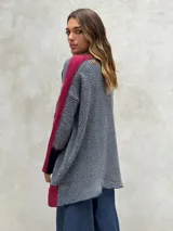 Sweater de punto con patrón de espiga en tonos beige y marrón, cuello alto, mangas largas con detalles en naranja y puños marrones.