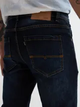 Jean de calce slim fit, color azul oscuro con detalles de desgaste y roturas.