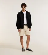 Campera masculina de estilo casual con cuello inglés, cierre frontal por cremallera, bolsillos laterales y ajuste elástico en el bajo. Presenta detalles de recortes en la parte superior delantera.