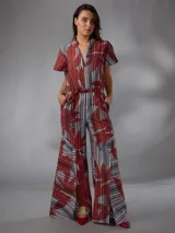 Mono de lino mezcla con estampado vegetal en tonos rojos, grises y blancos, de manga corta, escote en V y piernas amplias con cinto incorporado para ajustar la cintura.