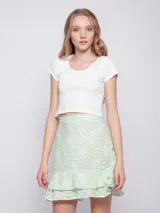 Minifalda verde con estampado de flores blancas y volados en el ruedo.