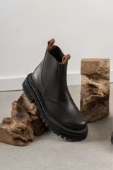 Botas tipo Chelsea de cuero color marrón con paneles elásticos laterales negros y suela track de goma negra con plataforma.