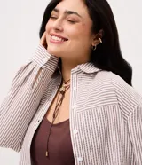 Camisa plus size alargada de Ashua, confeccionada en tela anarruga con diseño a rayas en tonos marrón y blanco. Presenta cuello inglés, cierre frontal con botones y mangas largas.