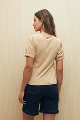 Remera de tejido acanalado color beige, con cuello redondo y mangas cortas abullonadas con puños elásticos.
