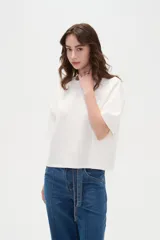Remera blanca de manga corta, con cuello redondo a la base y diseño holgado.