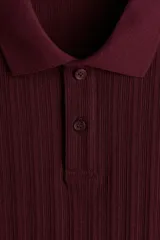 Remera polo de punto texturizado color bordó, de manga corta, con cuello y tapeta de dos botones. Corte ajustado slim fit.