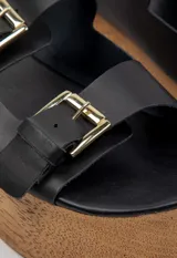 Sandalias negras de cuero con plataforma de madera y hebillas metálicas.