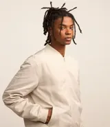 Campera bomber color beige, con cuello alto, cierre frontal con cremallera, bolsillos laterales y puños y cintura elastizados.