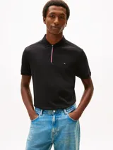 Chomba Tommy Hilfiger de corte regular, color negro, de manga corta, con cuello tipo polo y cierre de cremallera de un cuarto con detalles tricolor. Presenta logo bordado en el pecho.