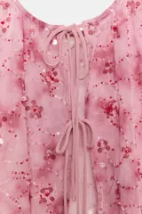 Top de tul semitransparente color rosado con estampado y bordado de lentejuelas a tono. Presenta escote redondo, tirantes anchos y cierre frontal con finas lazadas.