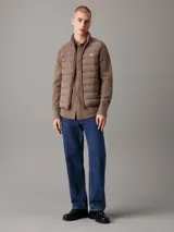 Chaleco acolchado marrón claro con cierre frontal con cremallera, cuello alto y bolsillos laterales.
