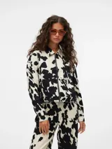 Chaqueta corta con cuello clásico, cierre frontal con cremallera, puños abotonados y estampado de manchas de vaca en blanco y negro.