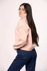 Buzo tejido de punto con cuello alto y cierre frontal parcial. Presenta mangas largas con puños acanalados y un diseño de corte holgado.