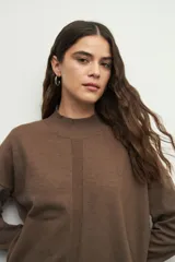 Polera de cuello alto y manga larga, confeccionada en tejido de punto color marrón, con detalle de costura vertical central y puños elastizados.