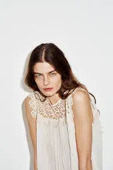 Blusa sin mangas de cuello redondo, con canesú superior de crochet y cuerpo plisado. Cuenta con forro interior y cierre trasero con botón.