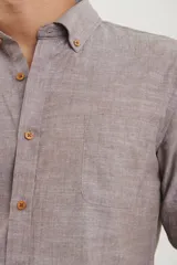 Camisa de manga larga con cuello abotonado, cierre frontal con botones y bolsillo en el pecho. Presenta un diseño de textura melange en tono azul piedra.
