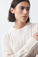 Vestido midi de punto en color gris, con diseño de tejido acanalado vertical, cuello redondo y mangas largas. Presenta una silueta recta y fluida.