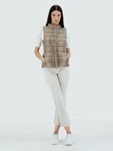 Chaleco puffer color beige, con cuello alto y cierre frontal con botones a presión.