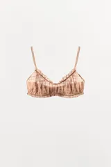 Bralette de escote redondo con tirantes finos ajustables, confeccionado en tejido semitransparente con diseño de elásticos fruncidos y acabados en volantes a tono.