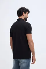 Remera polo verde militar de algodón pima, con cuello y puños acanalados, cierre frontal de tres botones y pequeño bordado de ave en el pecho.