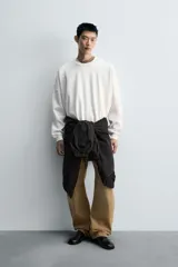 Sudadera negra de corte relaxed fit, confeccionada en tejido técnico interlock de algodón con elasticidad. Presenta cuello redondo, manga larga y una etiqueta aplicada en el bajo. Los acabados son en rib.