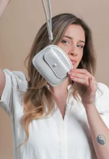 Monedero compacto de símil cuero con textura granulada, cuenta con un compartimento principal con cierre, correa de mano y un bolsillo frontal con solapa y botón a presión.