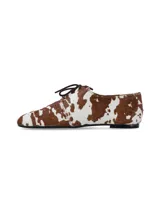 Zapato acordonado de estilo oxford con acabado en pelo sintético estampado con diseño de manchas de vaca en tonos marrón y blanco.