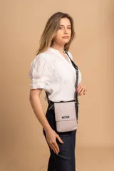 Bandolera pequeña tipo porta celular, confeccionada en material símil cuero color beige. Presenta una tapa frontal con logo de la marca, compartimento principal y correa larga regulable de cinta con inscripciones.