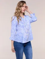 Blusa celeste con estampado efecto pincelada blanca, de corte semi holgado, escote en V con cuello solapa y media abotonadura frontal con botones nacarados. Presenta finas alforzas verticales en la pechera y mangas 3/4 con puños elastizados.