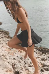Shorts de tiro medio confeccionados en tejido satinado de color negro, con diseño de bajo con vuelo y cierre lateral con cremallera oculta.