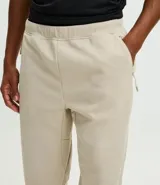 Pantalón deportivo de corte ajustado, confeccionado en tejido de poliéster texturizado color negro. Presenta cintura elástica con cordón de ajuste, bolsillos laterales con cierre y puños elásticos en los tobillos.
