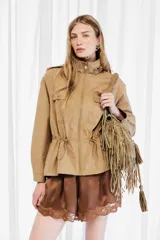 Campera estilo militar color tostado, confeccionada en 100% algodón, con cuello alto, cierre frontal de cremallera, bolsillos con solapa en el pecho y cordón ajustable en la cintura.