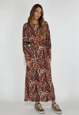 Vestido largo marrón con estampado abstracto en tonos beige y negro. Tiene corte recto, mangas largas y cinturón de la misma tela.