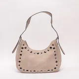 Bandolera beige de diseño curvilíneo, decorada con tachas metálicas plateadas a lo largo de los bordes. Cuenta con asa ajustable para el hombro y cierre superior.