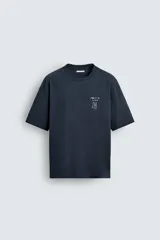 Camiseta relaxed fit color azul marino, con cuello redondo y manga corta. Presenta un estampado combinado a contraste en el delantero y la espalda. El estampado frontal es un texto en cursiva y un dibujo de tres figuras alargadas.