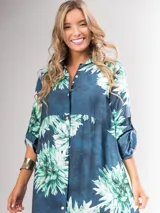 Vestido camisero largo con estampado floral en tonos rojos y negros, con cuello camisero, abotonadura frontal y mangas largas con puños abotonados.